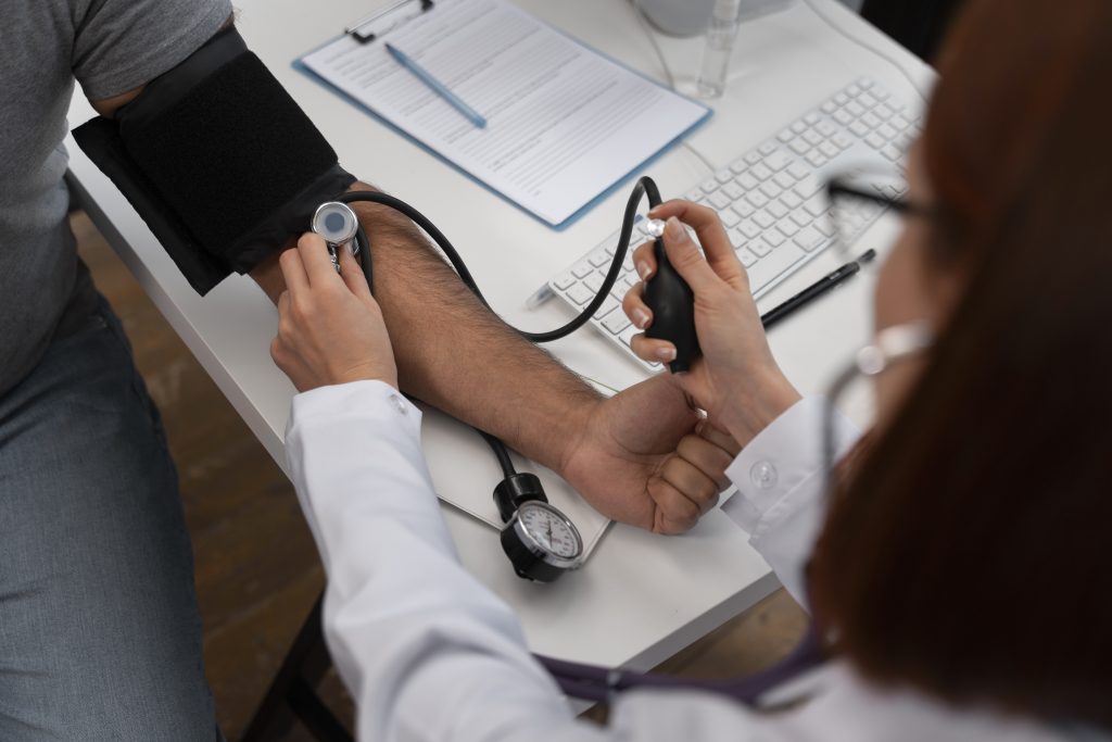 Médica realizando exames ocupacionais e aferindo a pressão de paciente em consultório