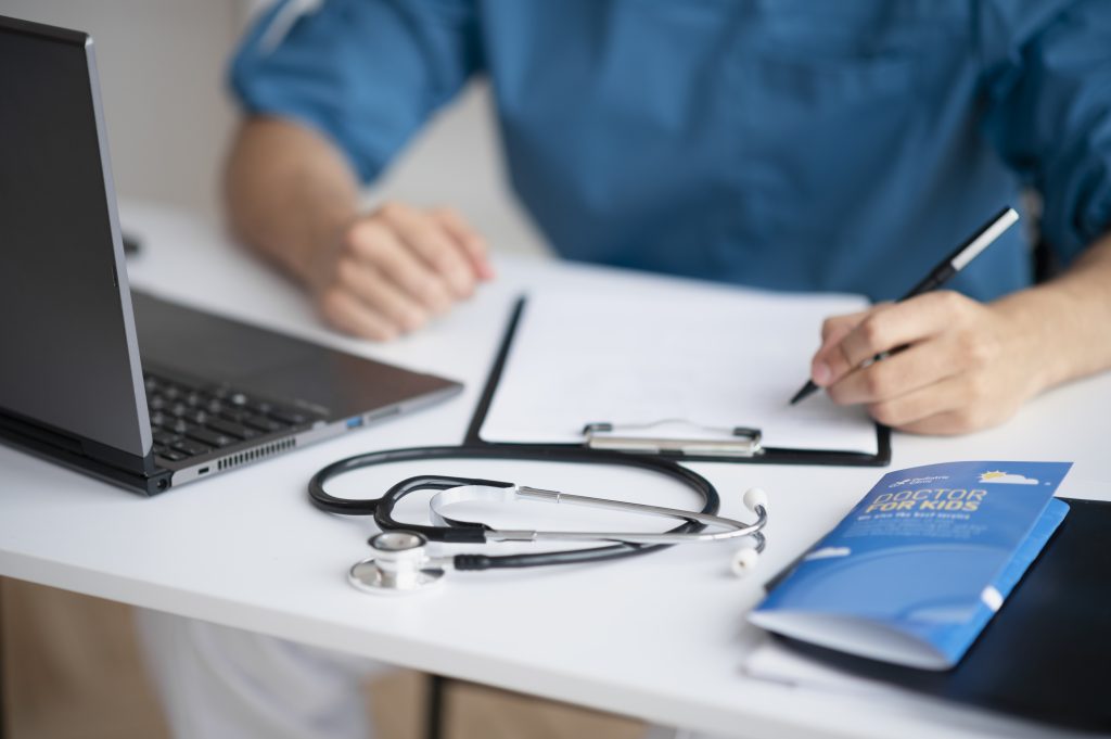 Médico do trabalho analisando documentos no consultório durante consulta de medicina do trabalho